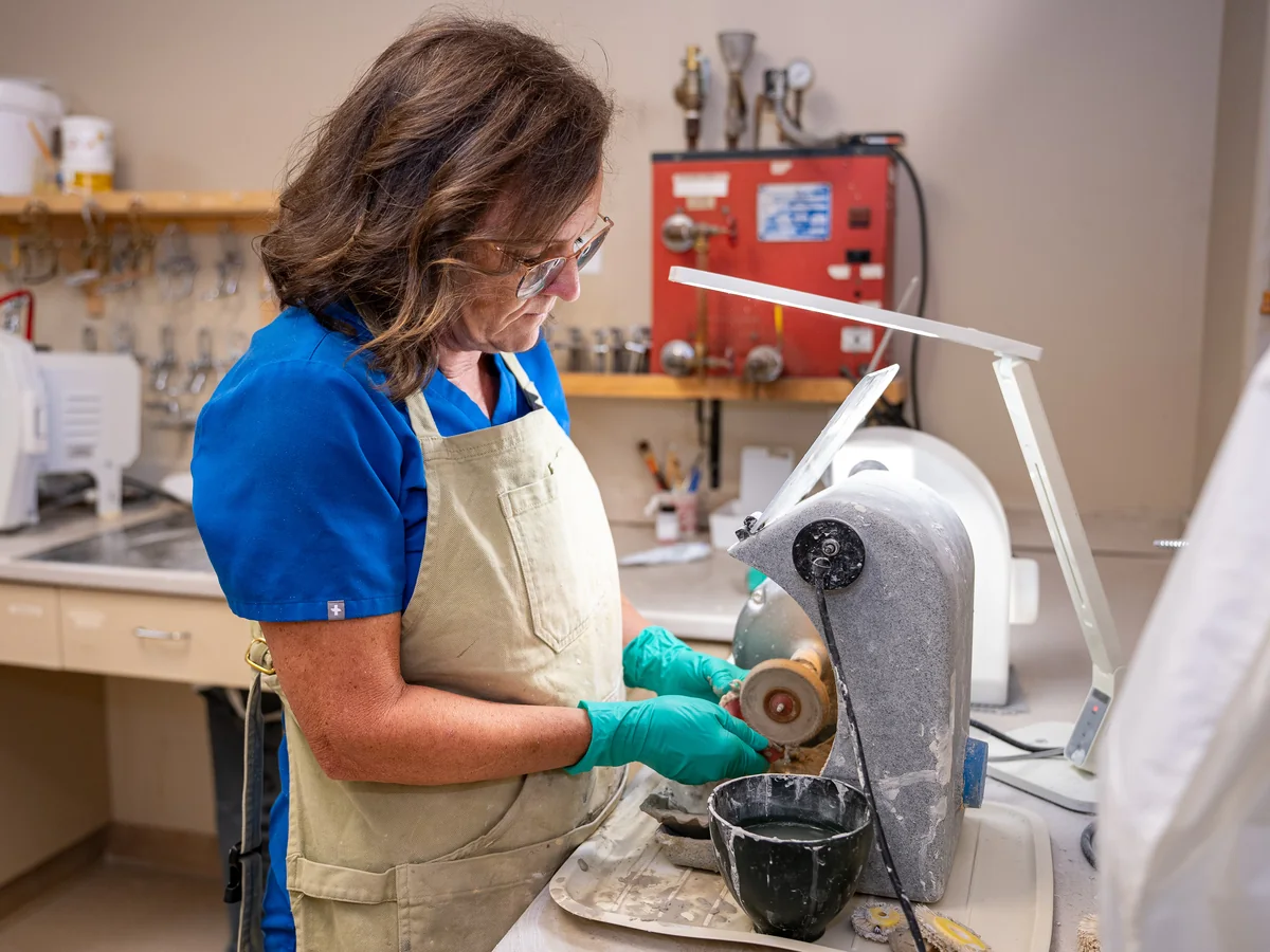 A technician shaping a denture in the practice's on-site laboratory