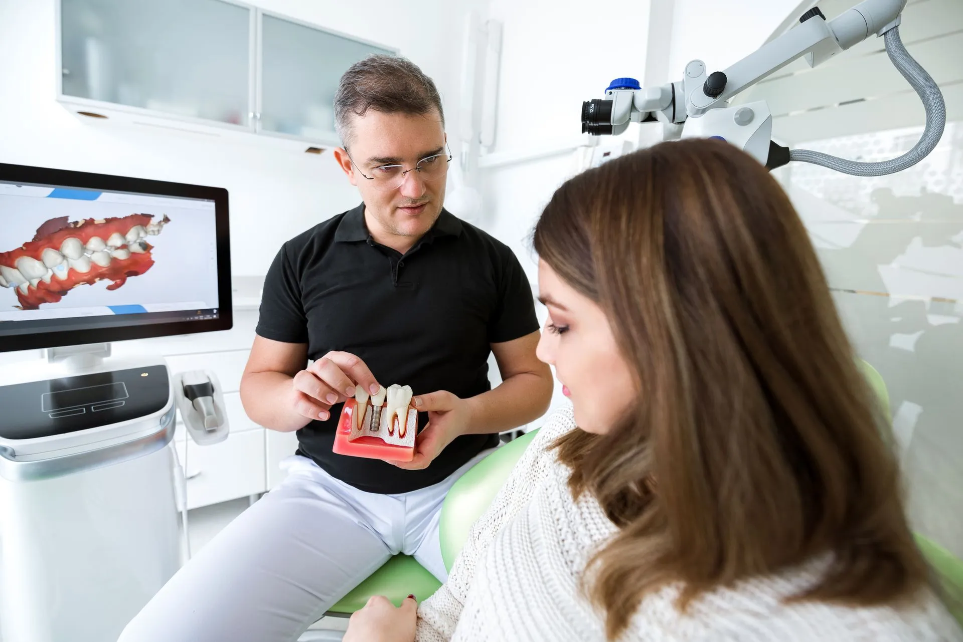 Dentist explaining a dental implant model to a patient