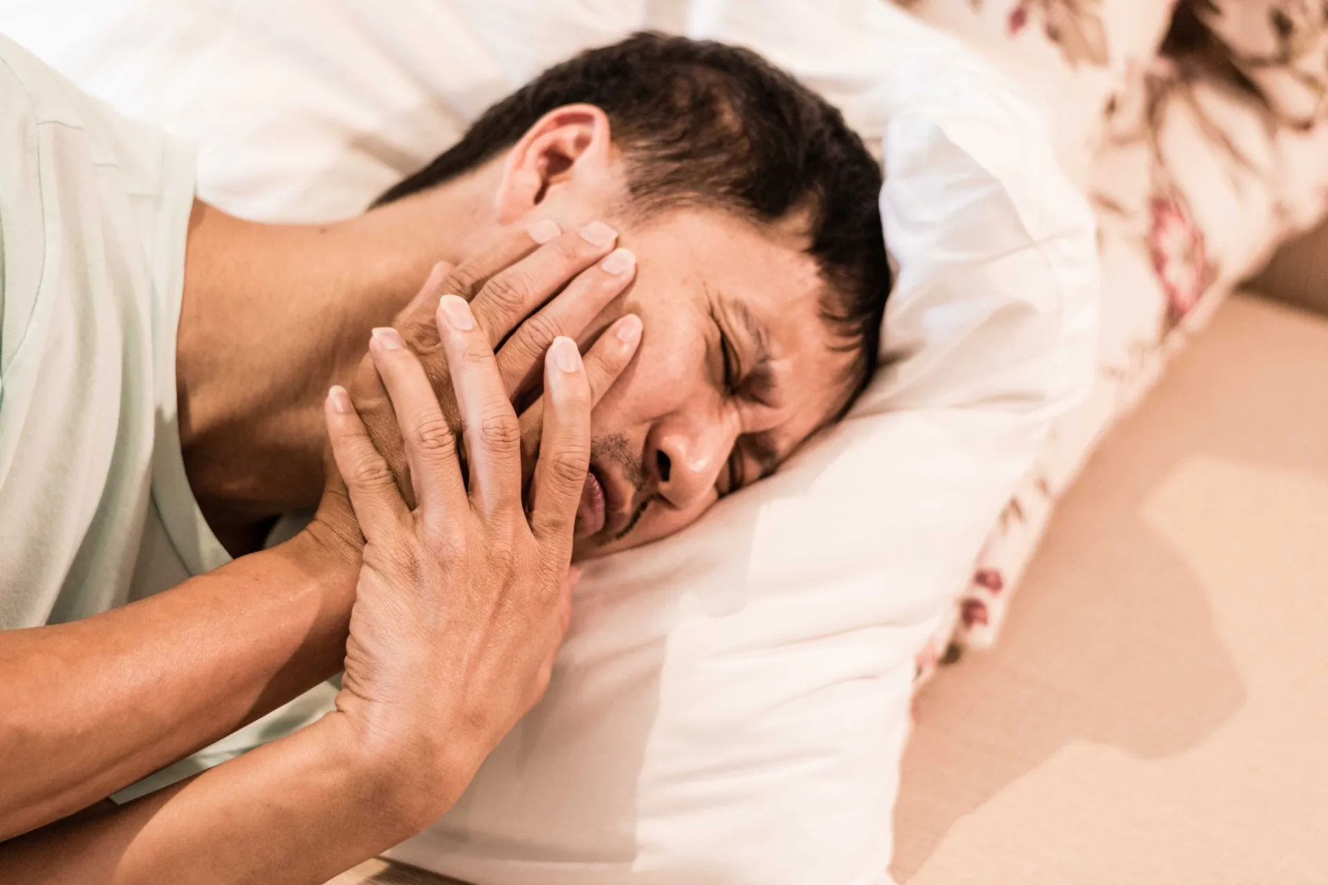 A person holding their jaw in discomfort